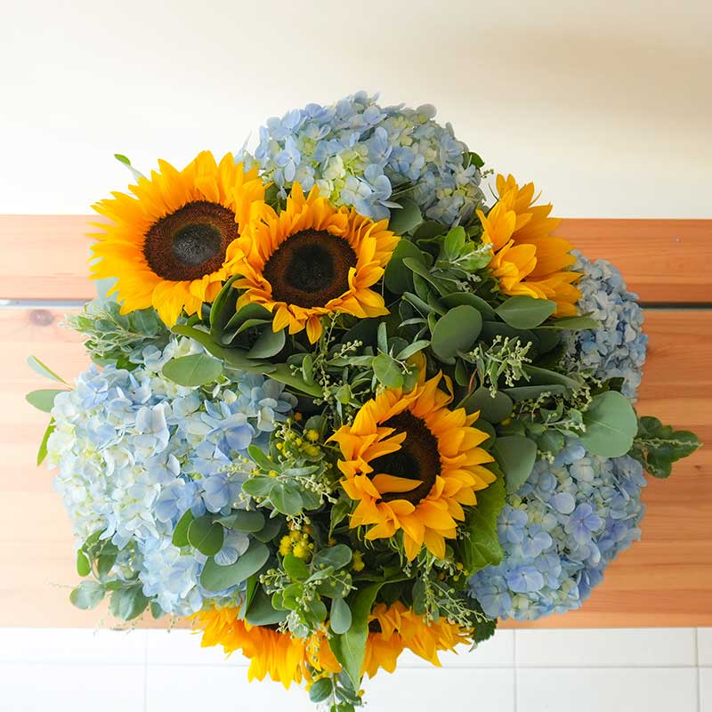arreglo de hortensias azules con girasoles