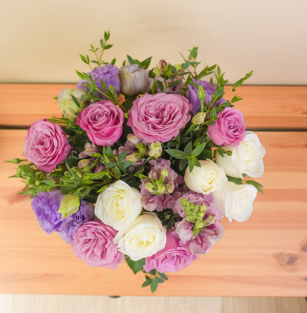 entrega de arreglos de flores con rosas moradas y blancas